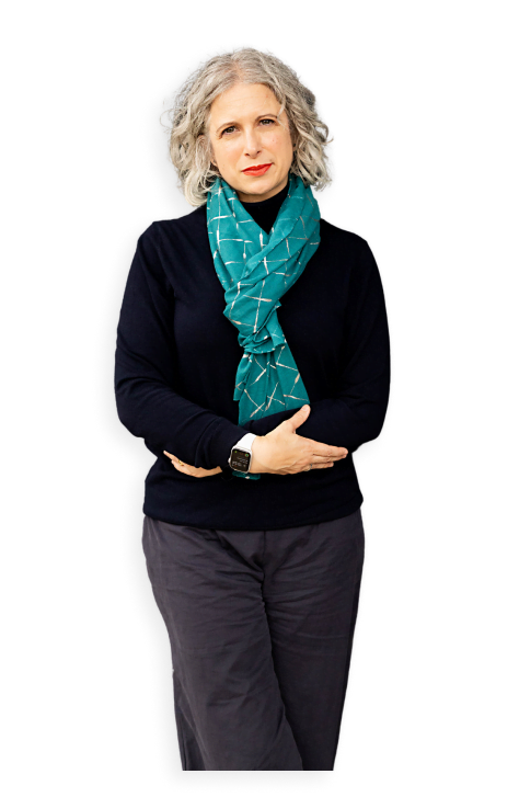 A woman with curly grey hair wearing a black top and trousers, teal patterned scarf, and a smartwatch stands against a white background—an inspiring image for the Accountants Growth Club or anyone seeking a business coach for accountants.